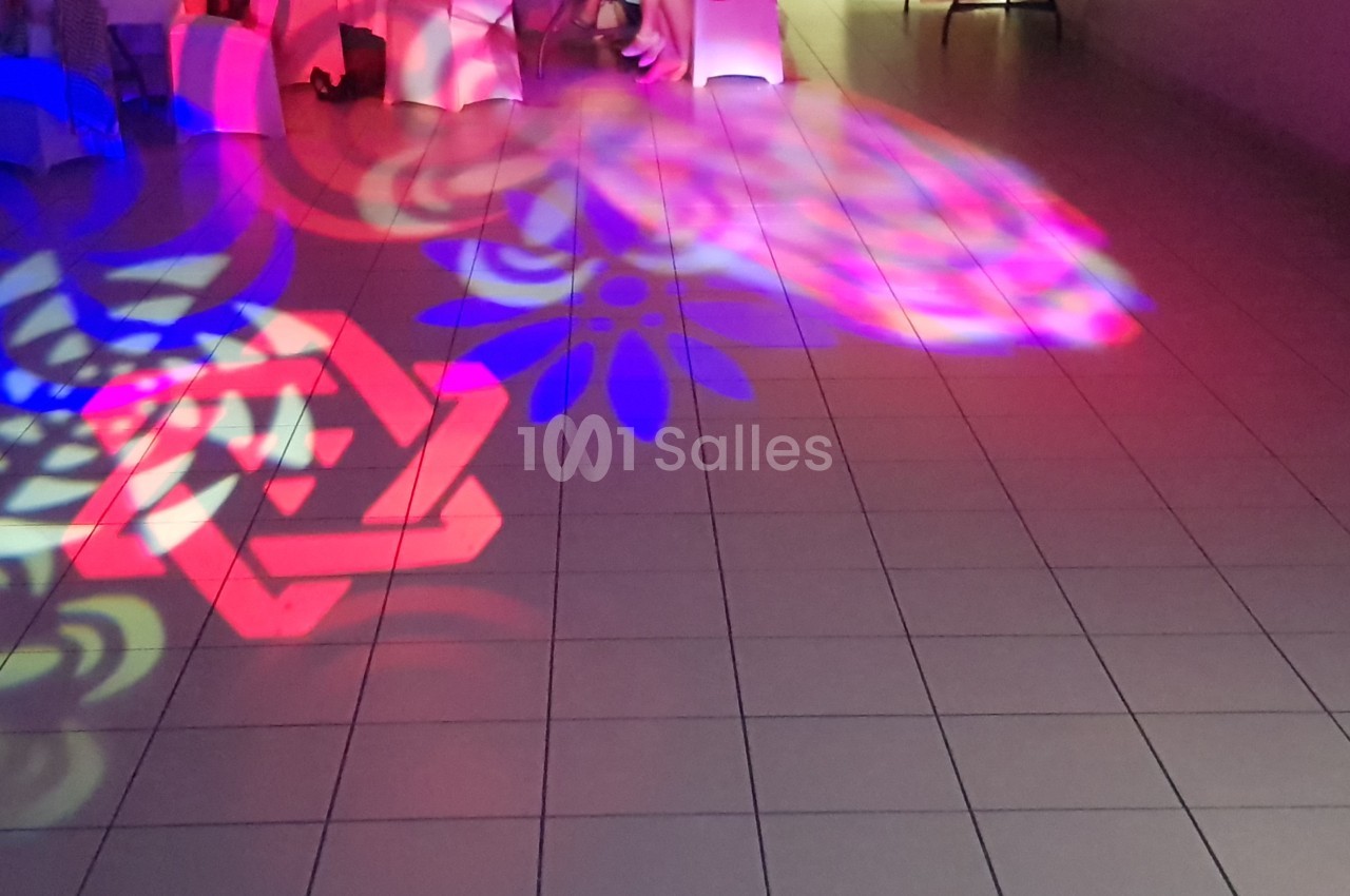 Lumières colorées projetées au sol formant des motifs géométriques et floraux dans une salle carrelée.