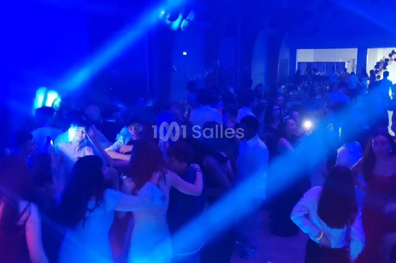 Groupe de personnes dansant dans une salle éclairée par des lumières bleues, ambiance festive.