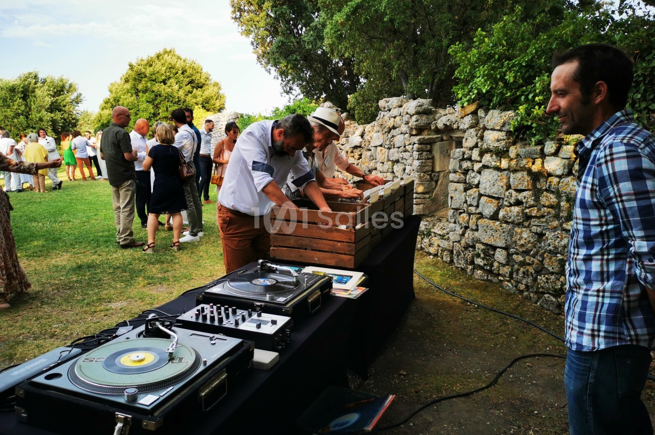 Des personnes participent à un événement en plein air près d'une table avec des platines vinyles et des caisses en bois.