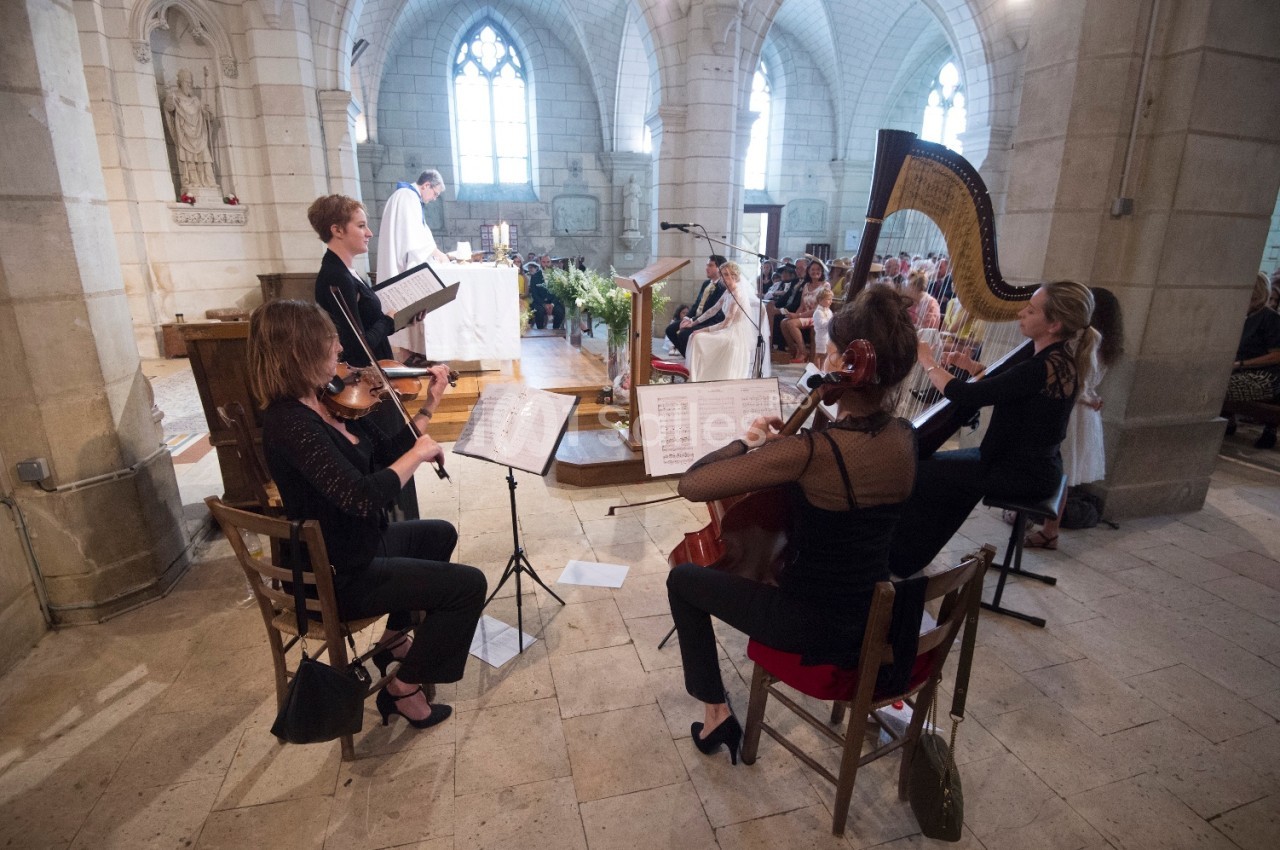Un quatuor à cordes et une harpiste jouent dans une église pendant une cérémonie religieuse.