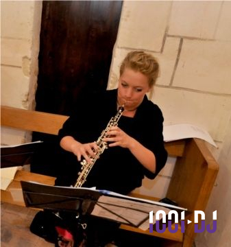 Une musicienne joue du hautbois assise sur un banc, entourée de partitions dans un cadre intérieur.