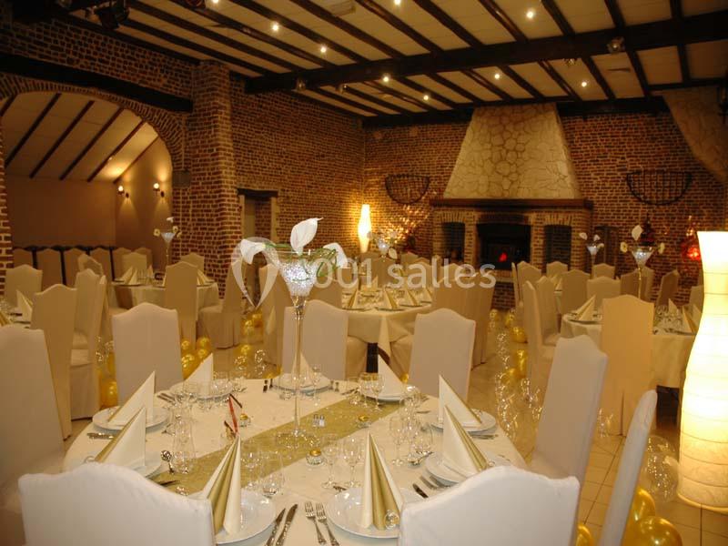 Salle de réception élégamment décorée avec des tables dressées, nappes blanches et centres de table fleuris.