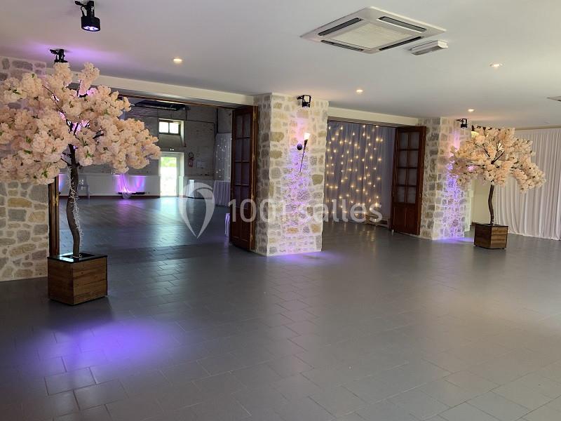 Salle lumineuse avec murs en pierre, sol carrelé, arbres décoratifs fleuris et éclairage tamisé.