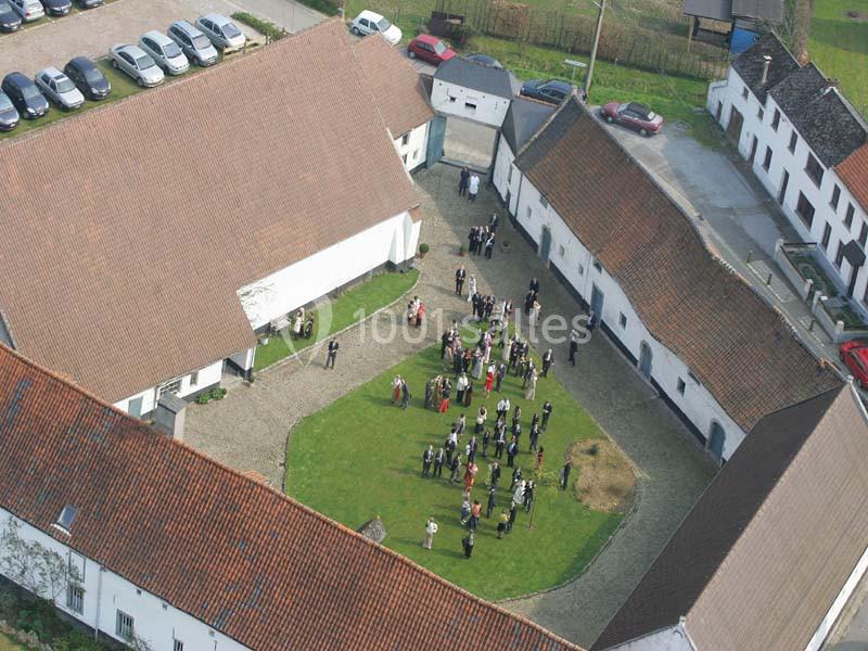 Vue aérienne d'une cour intérieure entourée de bâtiments avec un rassemblement de personnes au centre.