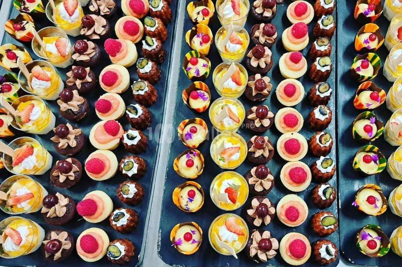 Plateaux garnis de divers desserts miniatures colorés, incluant des fruits, crèmes et décorations gourmandes.