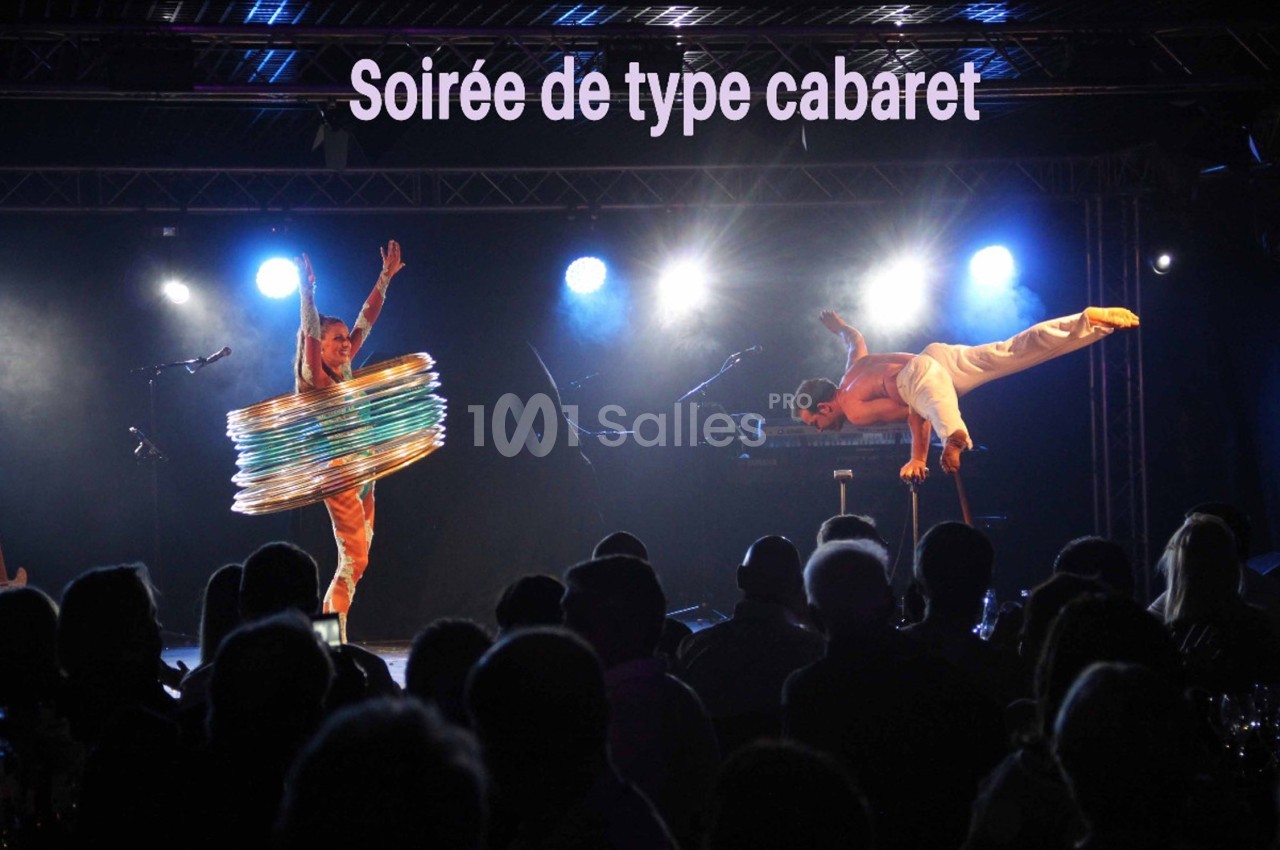 Deux artistes exécutent des performances acrobatiques sur scène lors d'une soirée cabaret, devant un public.