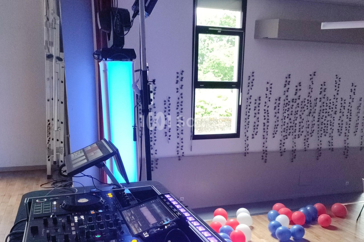Équipement de DJ installé dans une salle avec des ballons au sol et une fenêtre donnant sur l'extérieur.