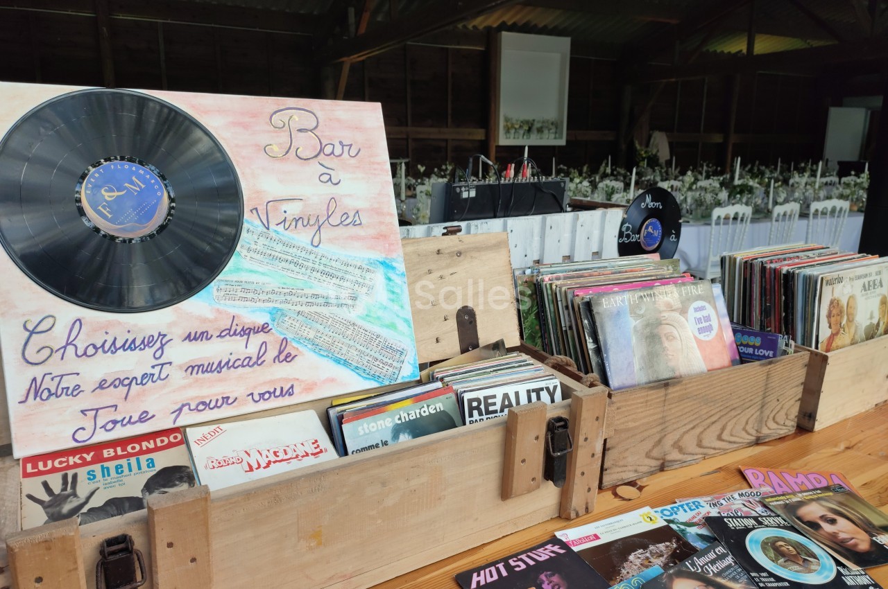 Disques vinyles exposés dans des caisses en bois, avec une pancarte indiquant ’Bar à Vinyles’ dans un cadre rustique.