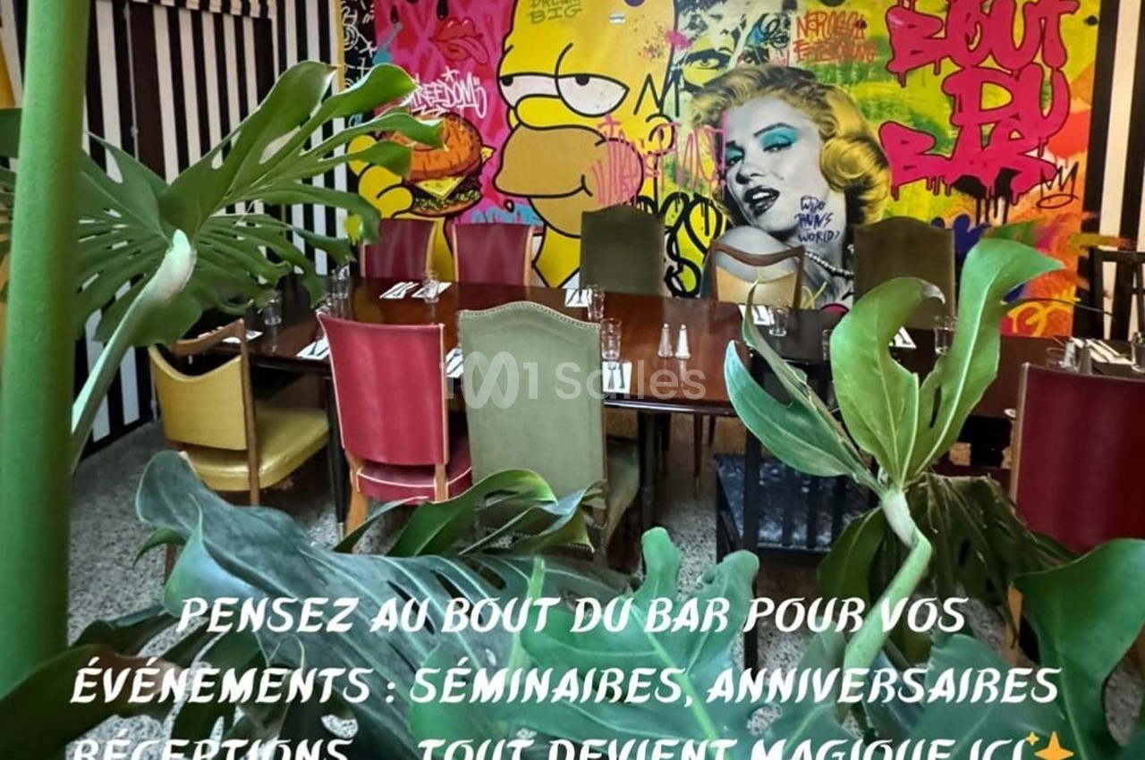 Salle colorée avec des tables dressées, entourée de plantes et décorée d'une fresque murale vive et artistique.
