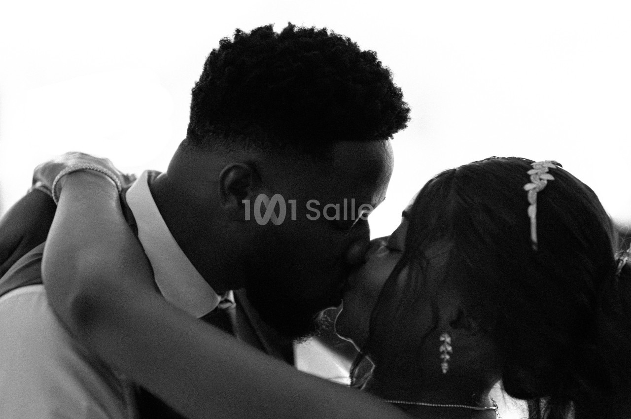 Un couple s'embrasse tendrement lors d'un moment intime, capturé en noir et blanc.