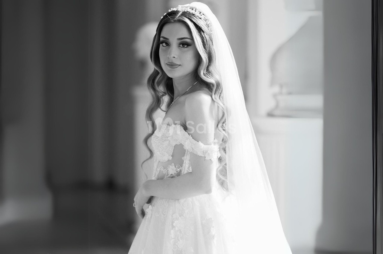 Femme en robe de mariée avec voile, posant dans un intérieur lumineux et élégant.