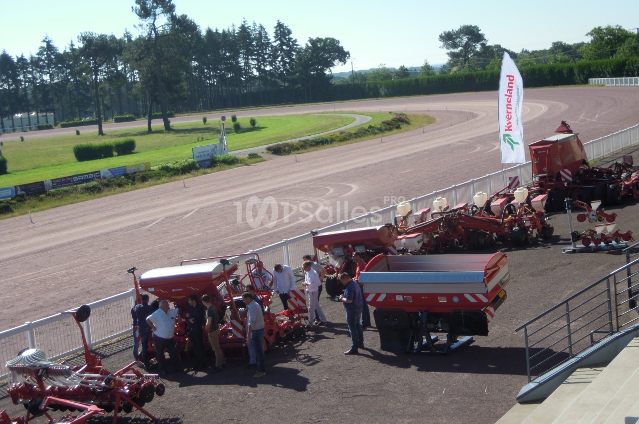 Vue d'une exposition de machines agricoles en plein air, avec des visiteurs observant les équipements exposés.