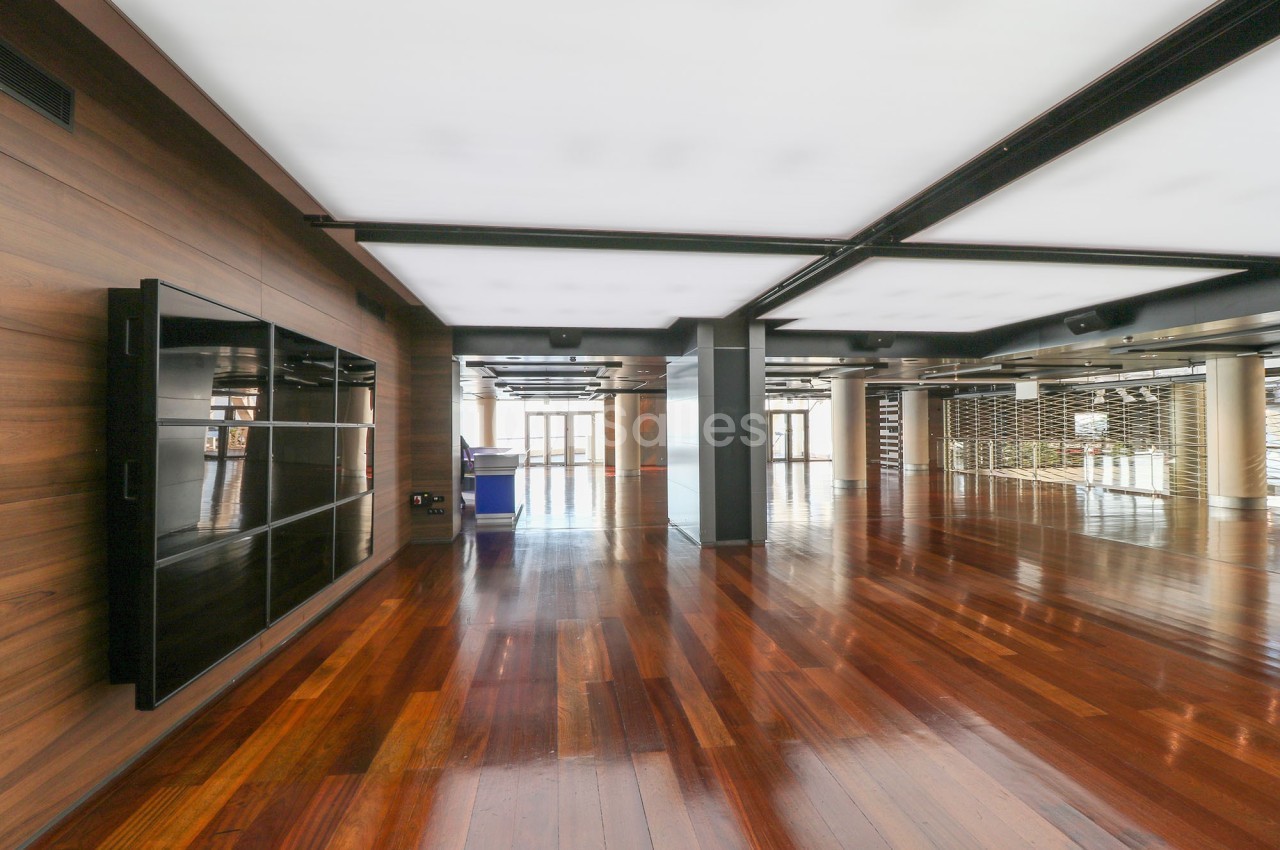 Salle moderne avec parquet en bois brillant, murs en bois, grandes fenêtres et plafond avec éclairage intégré.