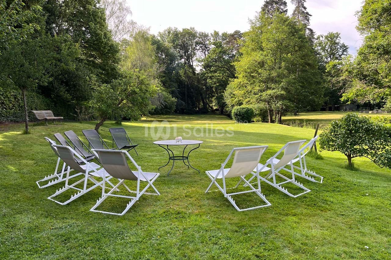 Chaises pliantes disposées en cercle autour d'une table basse sur une pelouse entourée d'arbres dans un jardin.