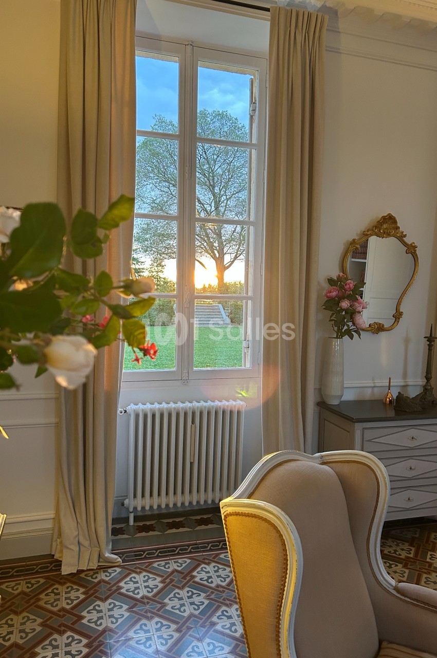 Vue d'une pièce élégante avec fauteuil, fenêtre donnant sur un paysage au coucher du soleil et décoration raffinée.