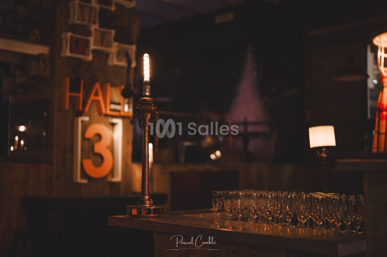 Lampe allumée sur un comptoir avec des verres à pied alignés, dans une ambiance tamisée de bar ou restaurant.