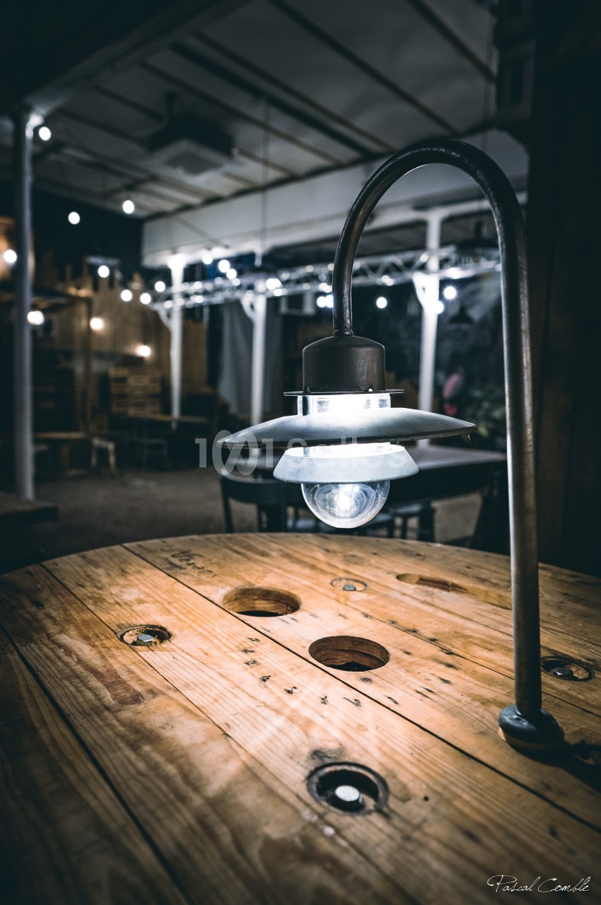 Lampe suspendue au-dessus d'une table en bois dans un espace intérieur faiblement éclairé.