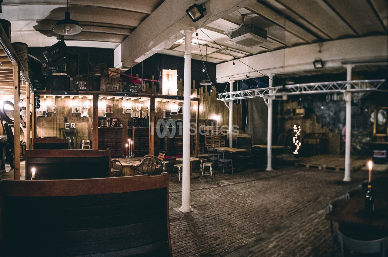 Intérieur d'un espace aménagé avec des tables en bois, éclairage tamisé et décor industriel.