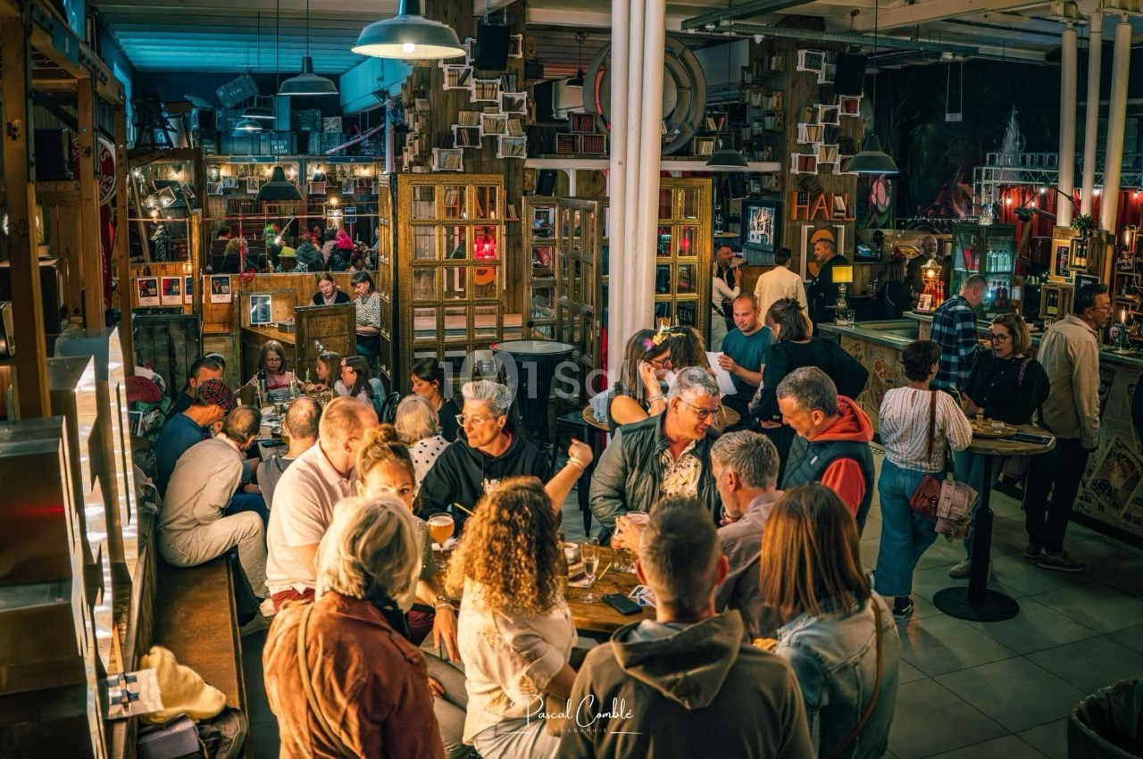 Groupe de personnes discutant et partageant un repas dans un restaurant animé à l'ambiance chaleureuse.