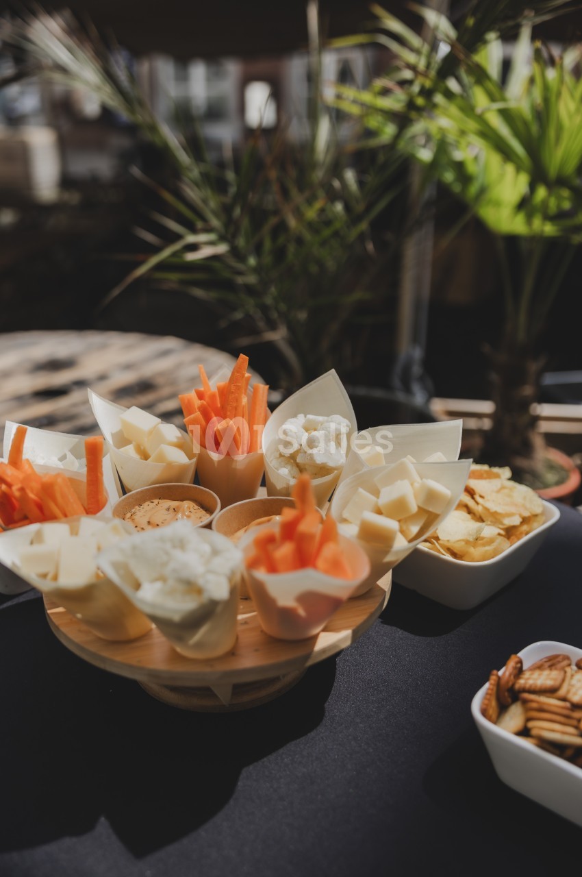 Cônes en papier contenant des cubes de fromage, bâtonnets de carotte et chou-fleur, accompagnés de chips et crackers.