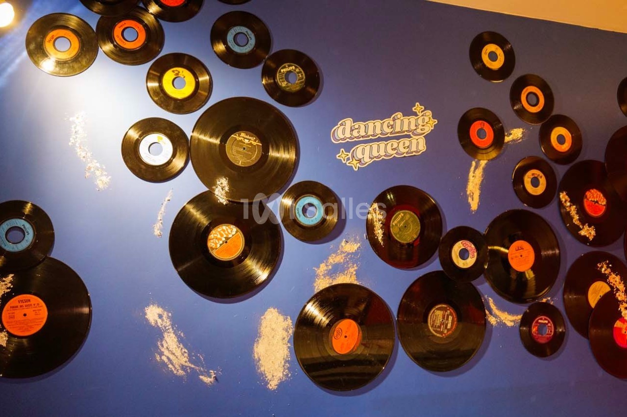 Disques vinyles accrochés sur un mur bleu avec l'inscription ’Dancing Queen’ en lettres blanches.