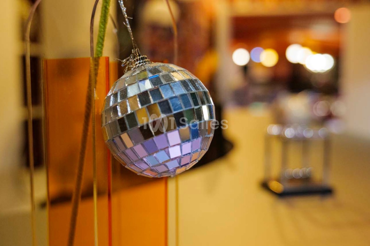 Boule à facettes suspendue, reflétant des lumières colorées dans un décor intérieur flou.