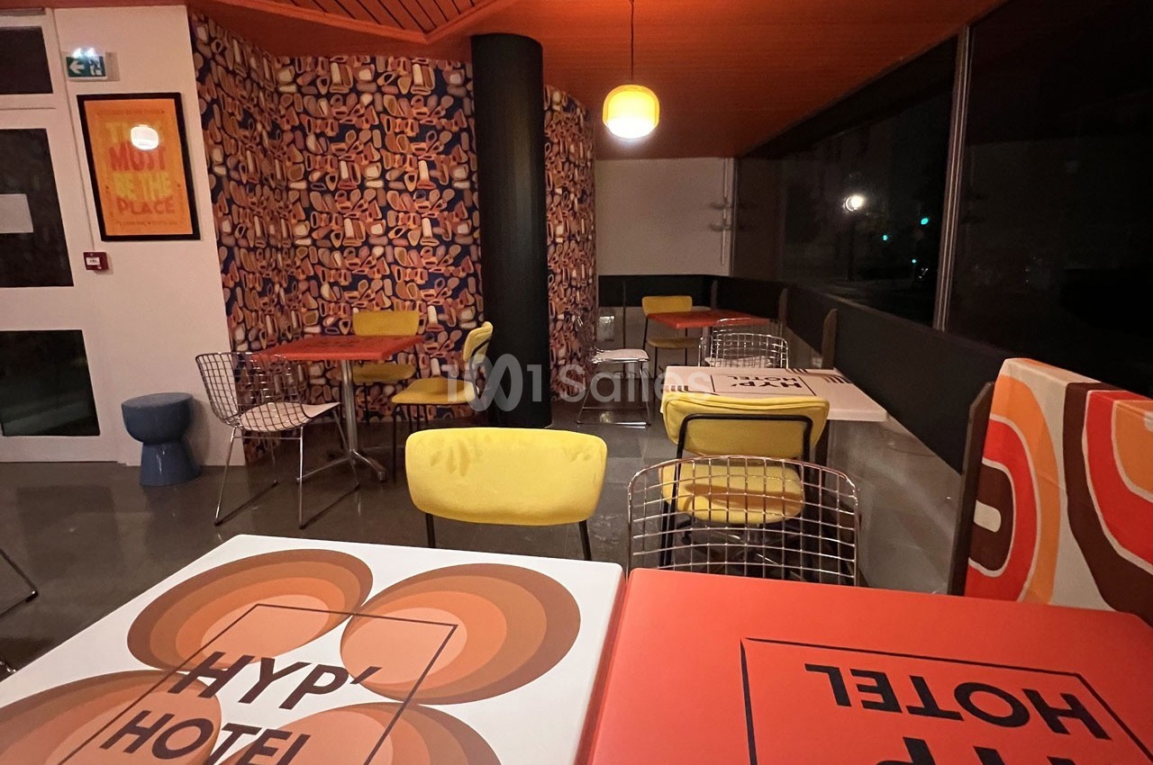 Espace de restauration coloré avec des tables décorées, des chaises modernes et une ambiance rétro.