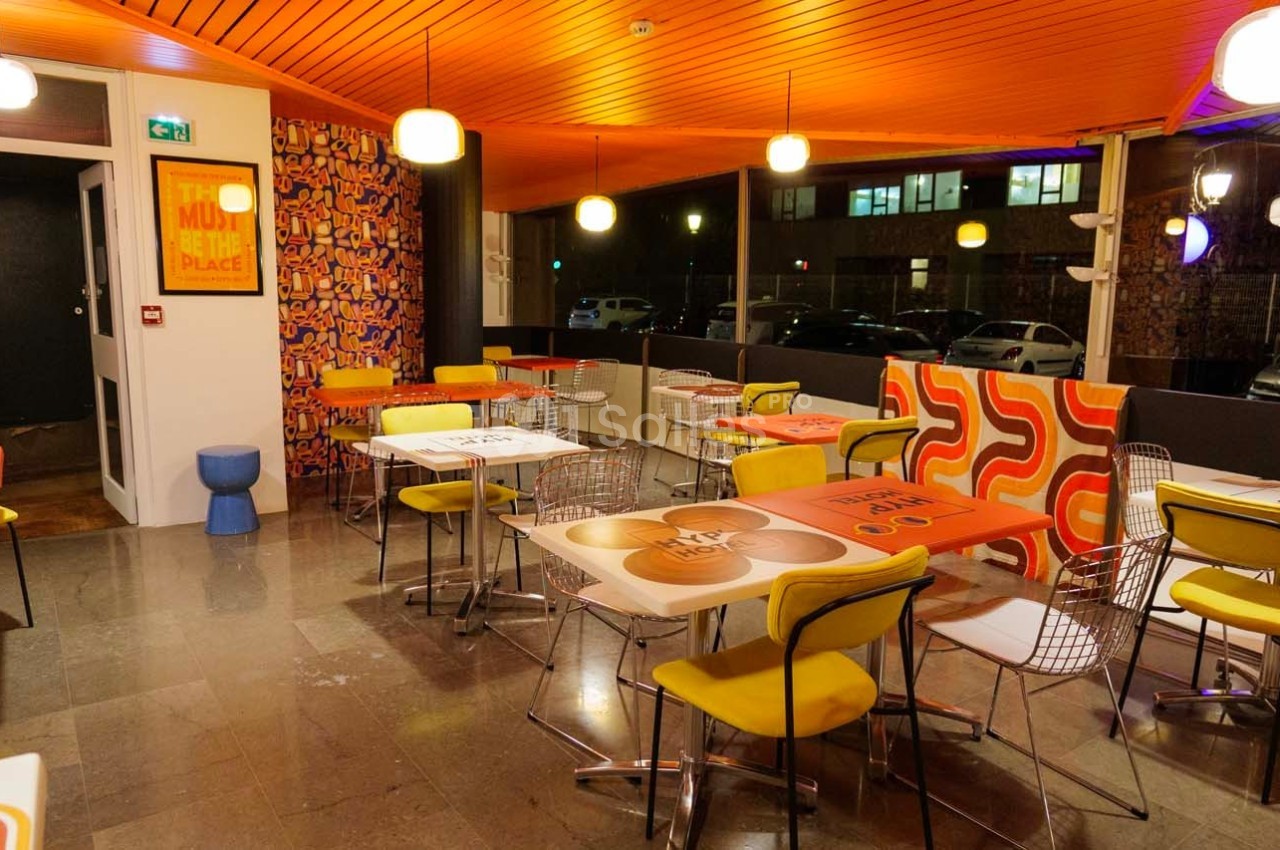 Salle de restaurant colorée avec des tables décorées, des chaises jaunes et un éclairage chaleureux.