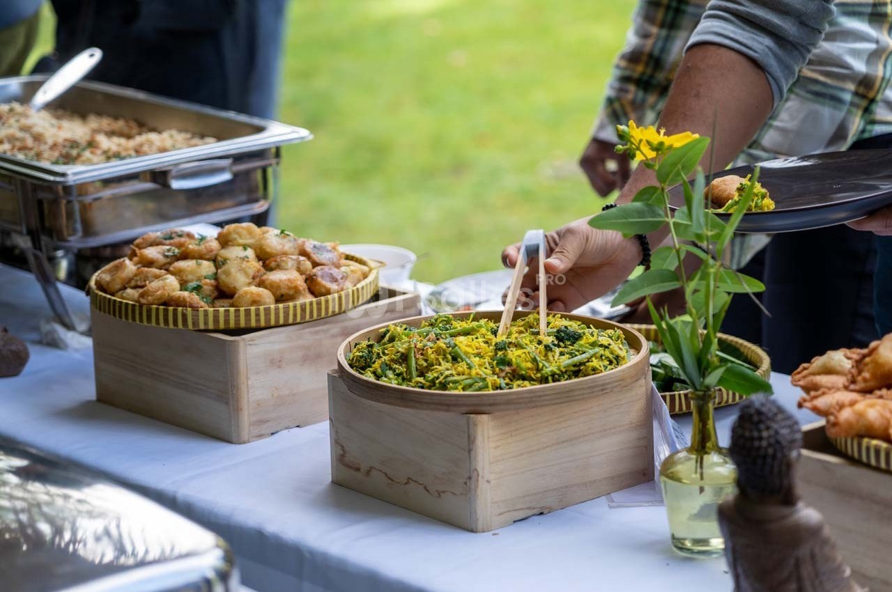 Buffet en plein air avec des plats variés, dont des salades et des beignets, sur une table blanche décorée de fleurs.