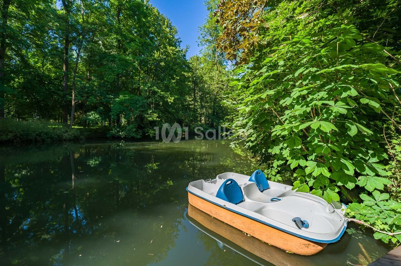 Pédalo amarré sur une rivière calme entourée de végétation dense et d'arbres verdoyants.