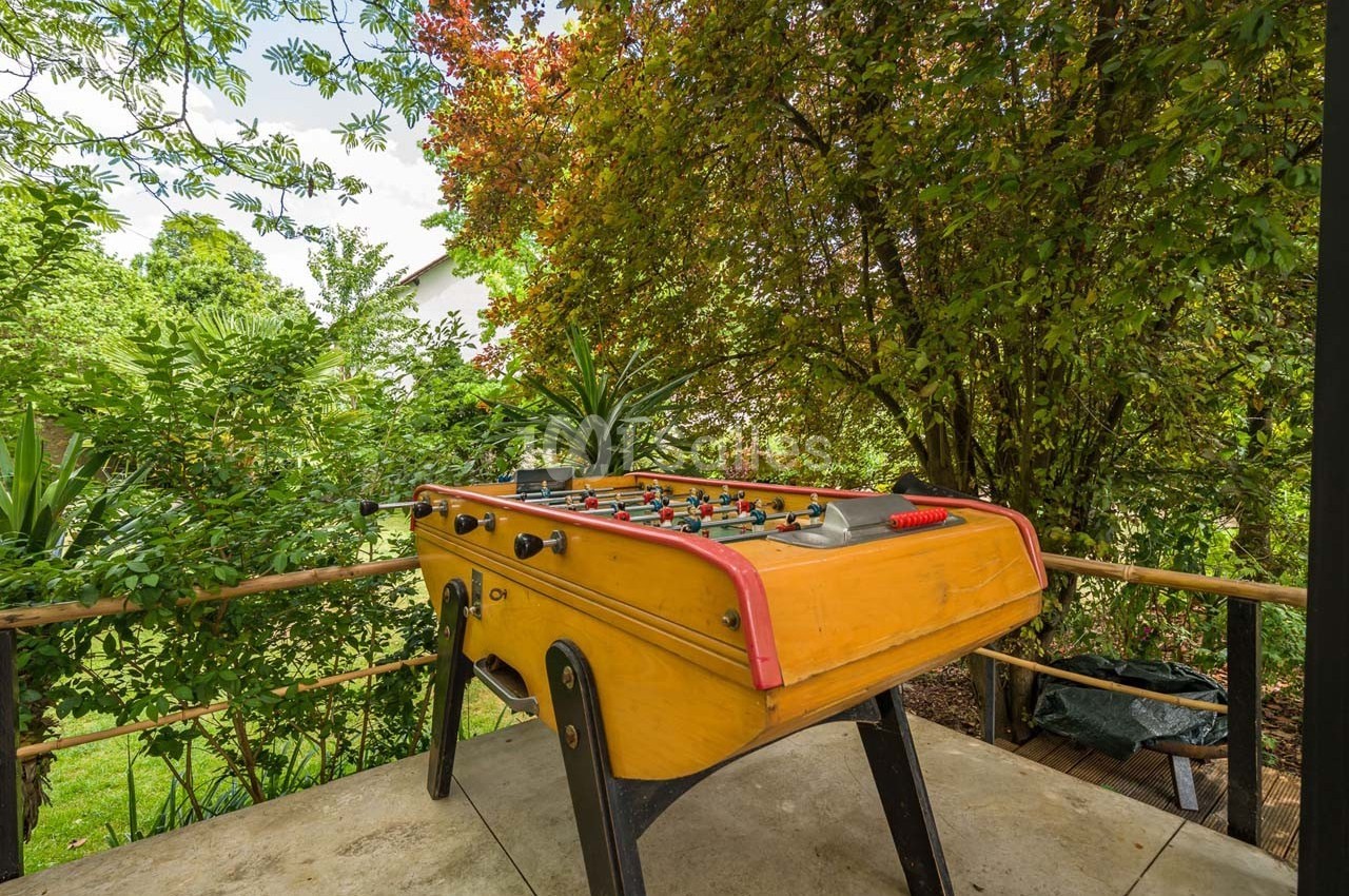 Baby-foot en bois installé sur une terrasse entourée de végétation luxuriante.