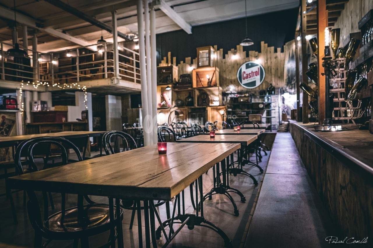Salle de restaurant au style industriel avec tables en bois, chaises métalliques et décoration rétro.