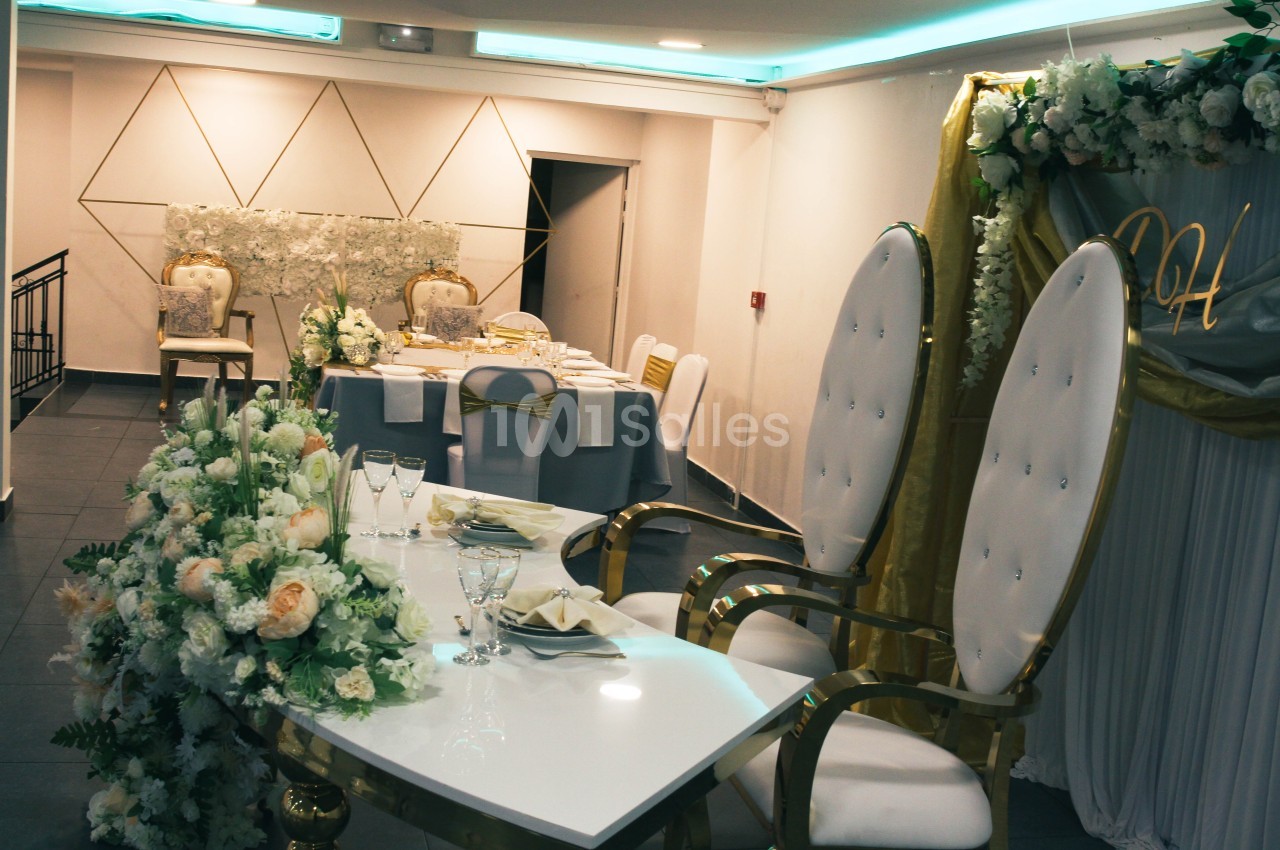 Salle de réception décorée avec des fleurs blanches et des chaises élégantes, prête pour un événement festif.