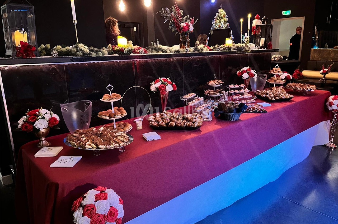 Table garnie de pâtisseries et desserts variés dans un décor festif avec guirlandes et bougies.