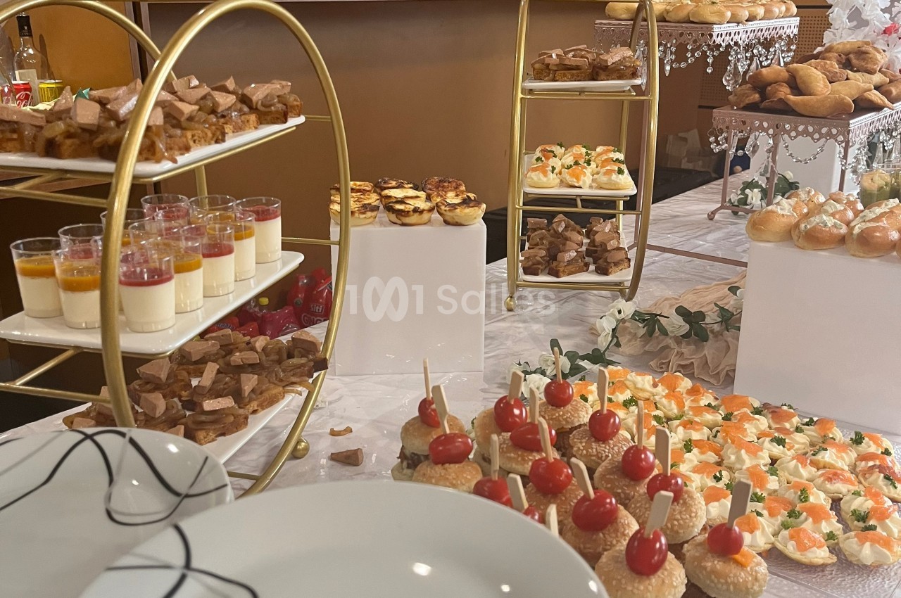 Buffet de réception avec verrines, mini-sandwichs, canapés et autres amuse-bouches disposés sur des présentoirs.