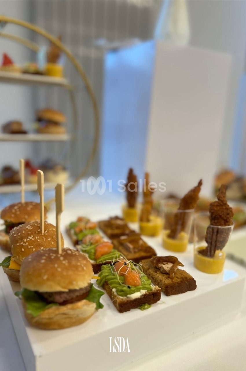 Plateau de mini-burgers, toasts garnis et verrines, présenté sur une table lors d'un buffet ou cocktail.