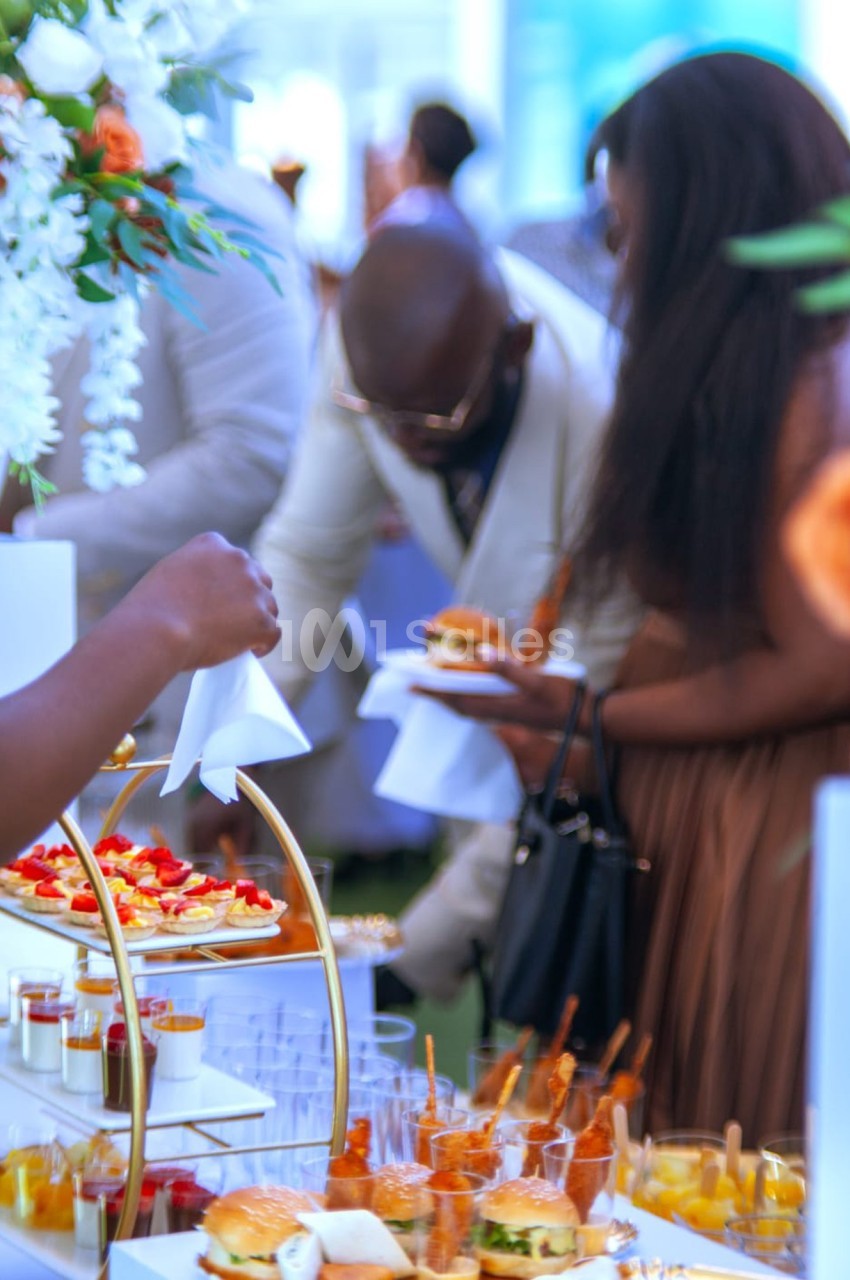 Personnes se servant à un buffet avec des plats variés, dont des verrines et des mini-burgers, dans un cadre élégant.