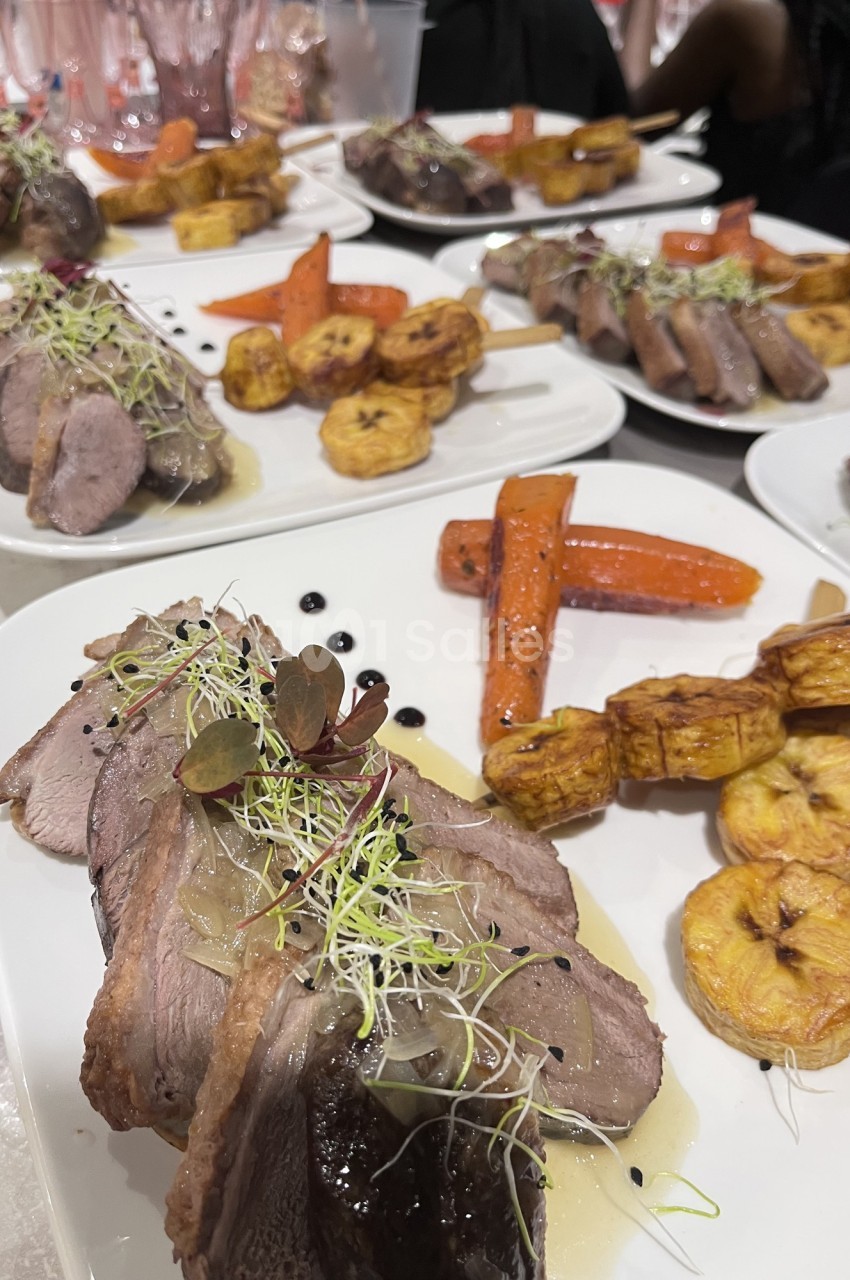 Assiettes de viande tranchée garnies de carottes, bananes plantains et pousses, servies avec une sauce.