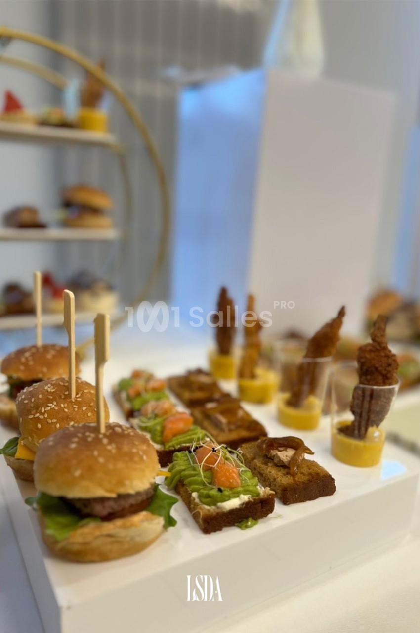Plateau de mini-burgers, toasts garnis et verrines disposés sur une table pour un buffet ou un événement.