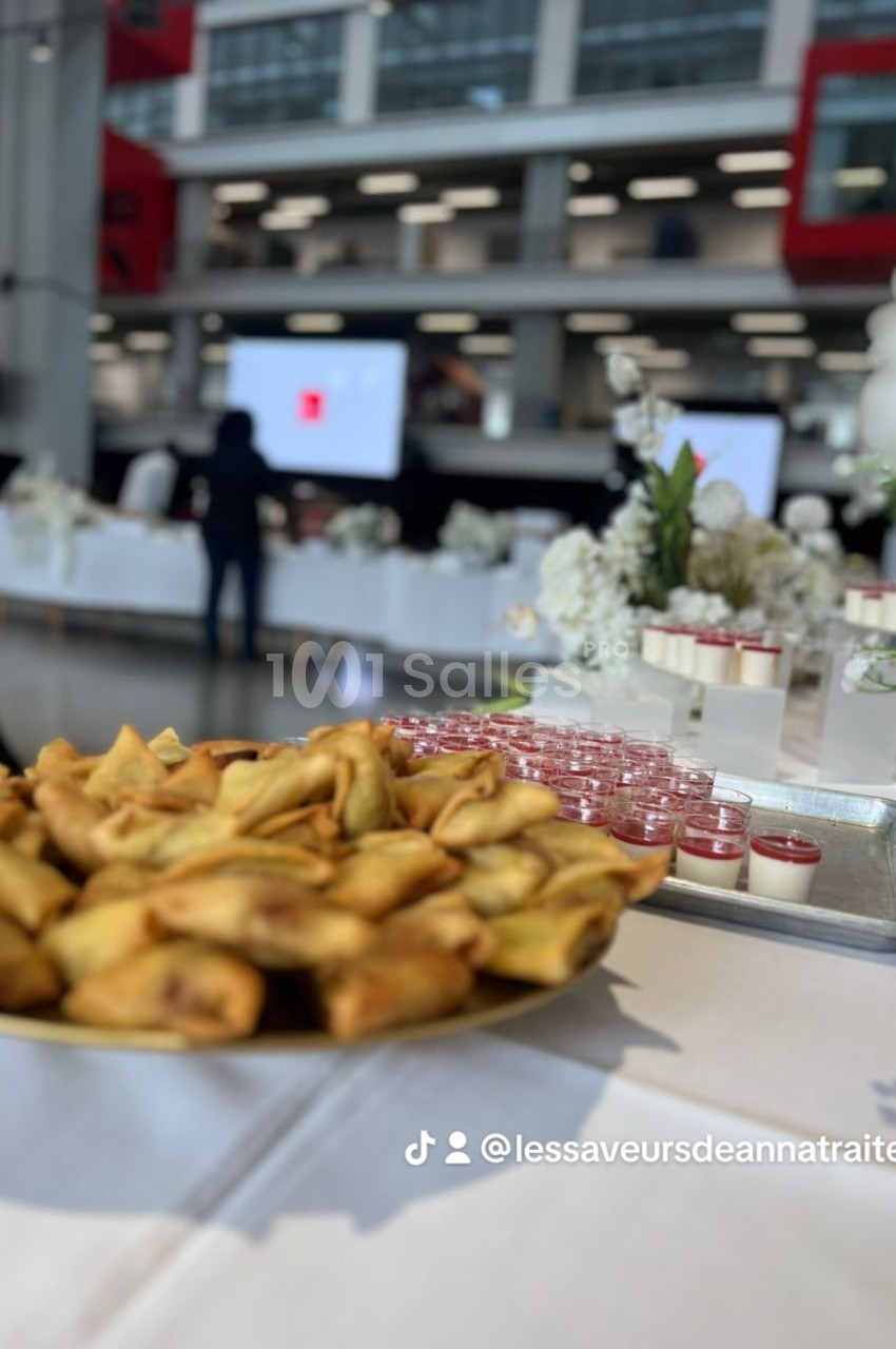 Assortiment de samoussas dorés et verrines disposés sur une table lors d'un événement dans un espace moderne.