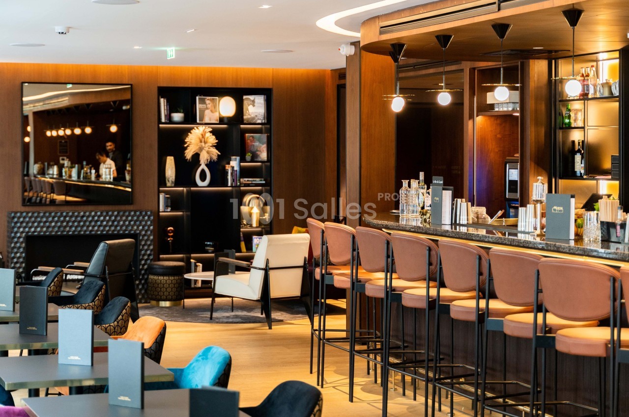 Bar moderne avec comptoir en marbre, tabourets hauts, étagères décoratives et ambiance chaleureuse.