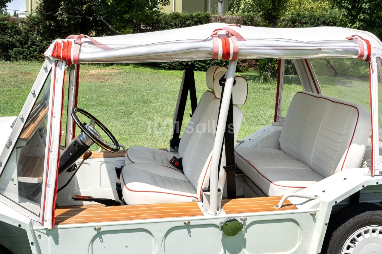 Vue latérale intérieure d'une voiture décapotable vintage avec sièges blancs bordés de rouge et toit en toile.