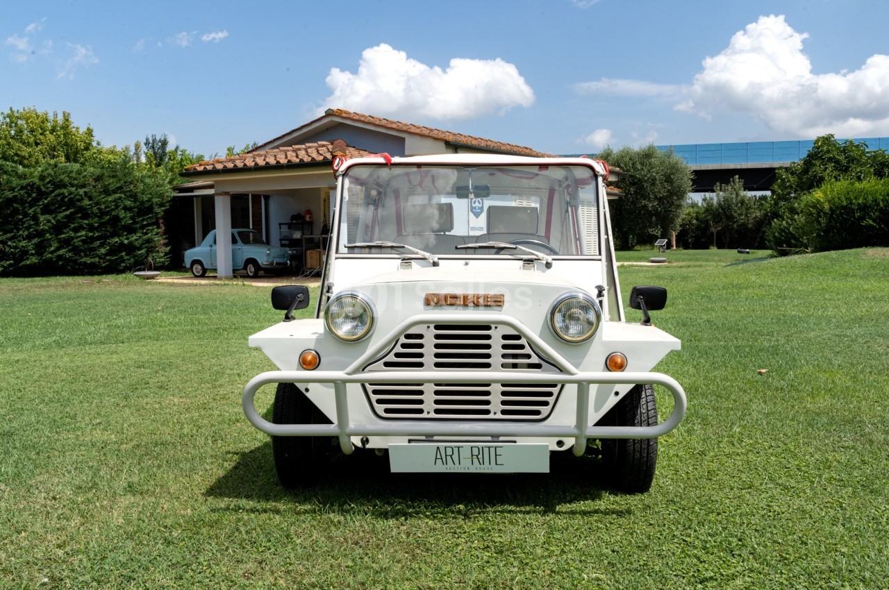 Voiture blanche stationnée sur une pelouse devant une maison avec un ciel bleu en arrière-plan.