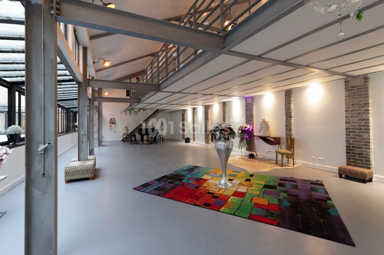 Intérieur spacieux et lumineux avec mezzanine, murs en briques, tapis coloré et mobilier moderne.