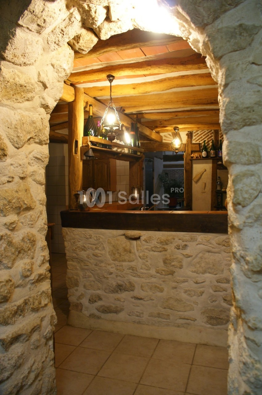 Vue d'un bar rustique en pierre et bois avec éclairage suspendu dans une pièce au style traditionnel.