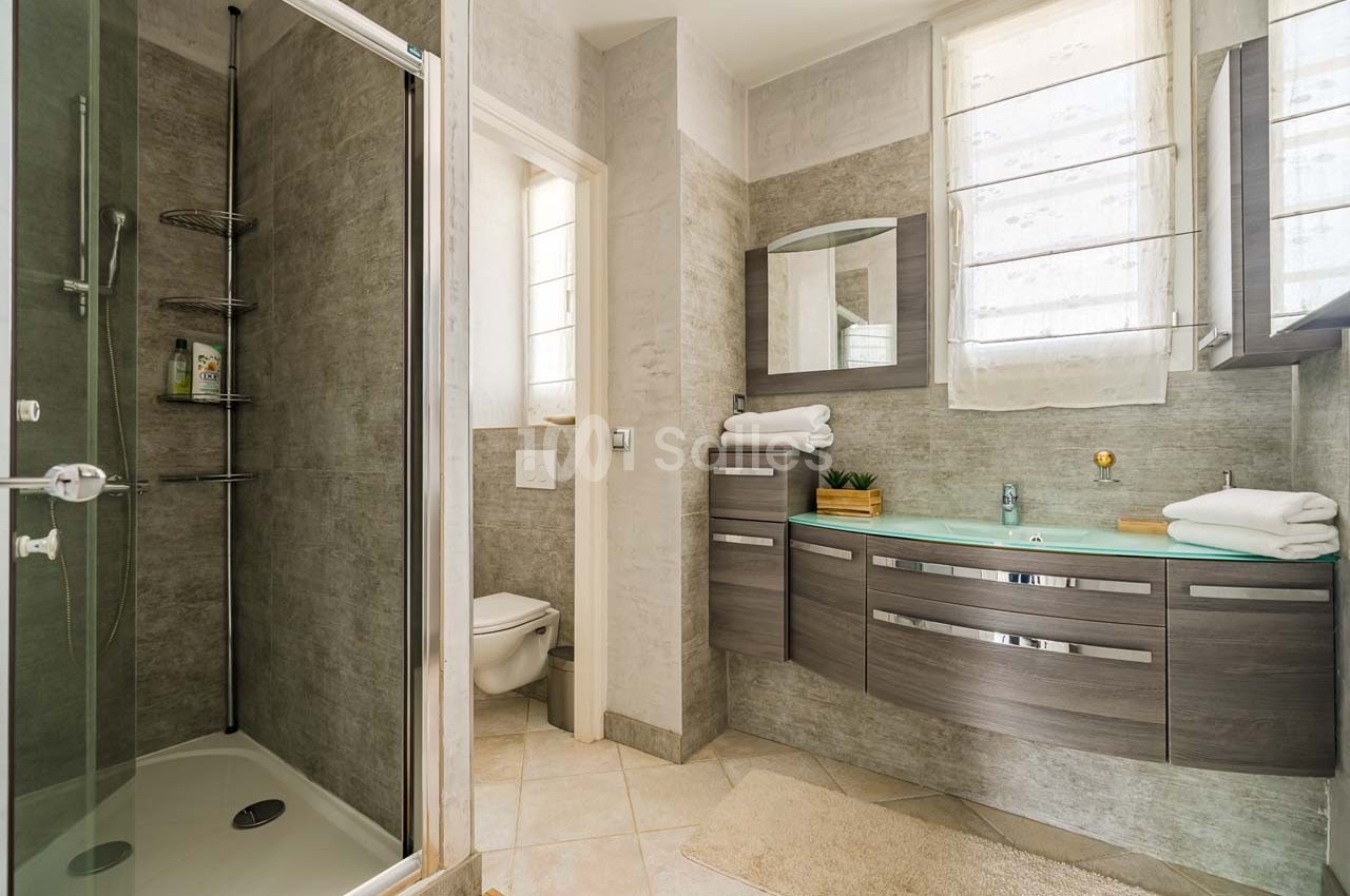 Salle de bain moderne avec douche à l'italienne, lavabo avec meuble en bois foncé et toilettes séparées.