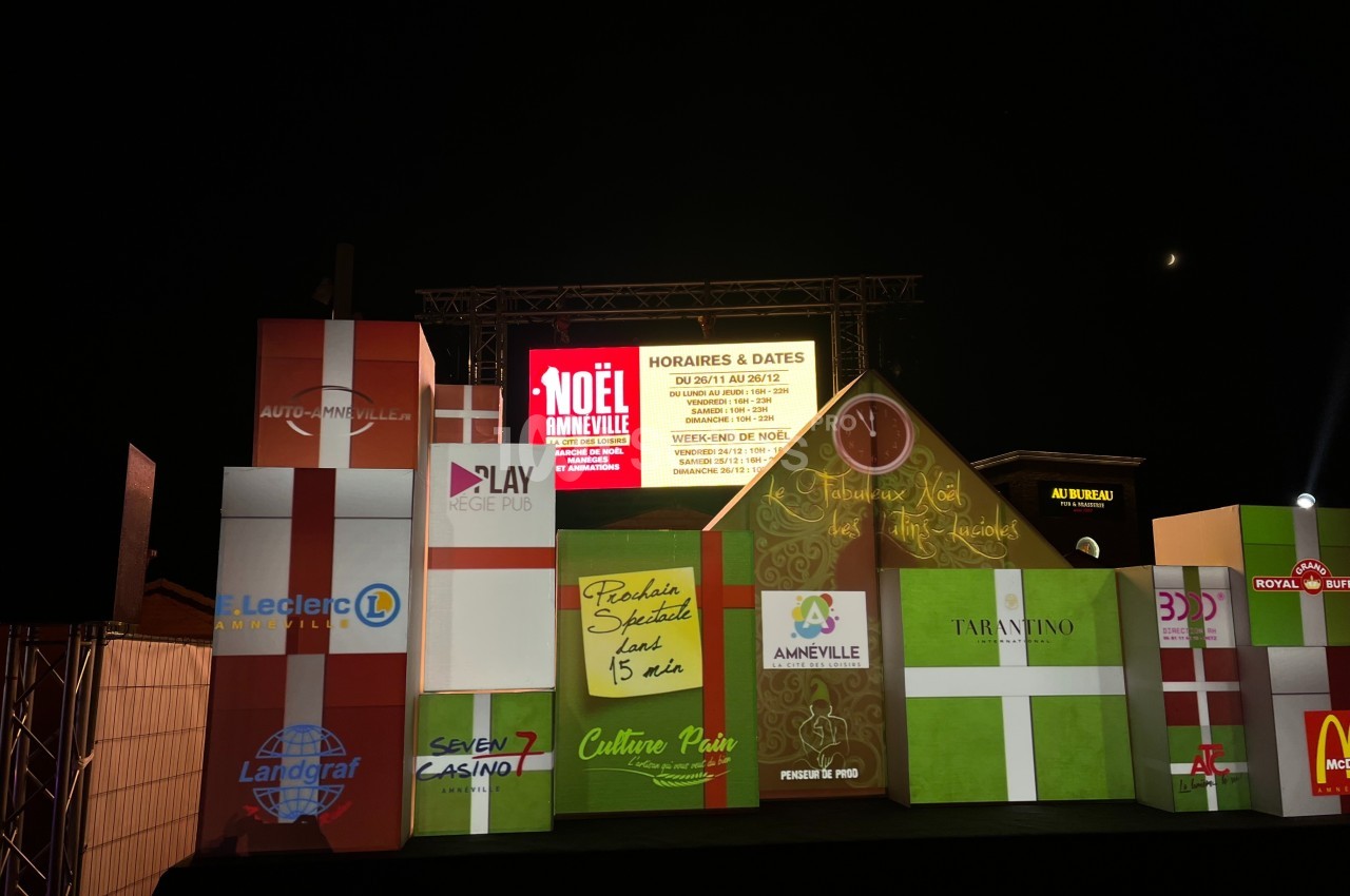 Façade illuminée avec des cubes décoratifs affichant des logos et informations sur un événement de Noël à Amnéville.