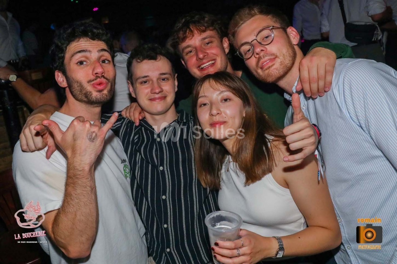 Un groupe de cinq jeunes adultes souriants posant ensemble dans un environnement festif.
