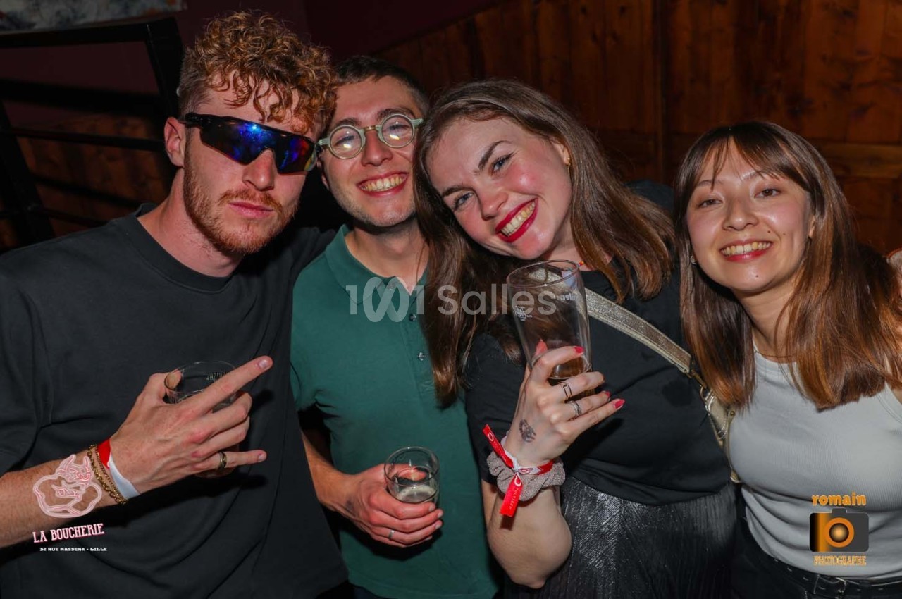 Quatre personnes souriantes posant avec des verres à la main dans un environnement festif.