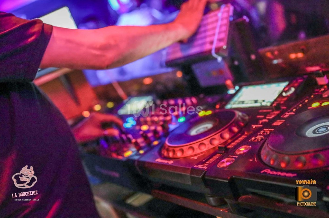 Un DJ mixant sur une table de mixage avec des lumières colorées en arrière-plan.